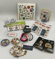 Lot items arranged including pins, bracelets, key tags, tattoos, collectible figure, and cards.
