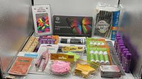 Photo showing various new office supplies including glue sticks, pens, face paint, calculator, tape dispenser and sticky notes.