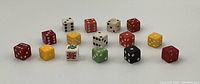 Photo showing 15 vintage dice of multiple colors arranged in two rows on a white surface.