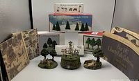 Full lot showing Liberty Falls miniature trees, musical figurine, boxed Americana accessory sets, and folded newspaper advertisements.