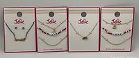 Photo shows four new Justice jewelry sets each with layered necklaces and various word and charm pendants. Each set displayed on branded cards.