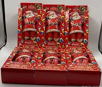 Six Coca Cola Santa collector tins in original packaging, each containing two decks of playing cards.