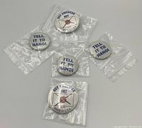 Photo of 5 vintage political button pins, 3 "Tell It To Hanoi" and 2 "Buy American Not", all individually bagged in clear plastic sleeves.