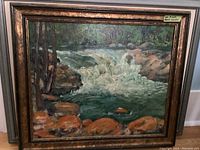 Framed oil painting showing a river with rocks and trees, signed by C E Moule.