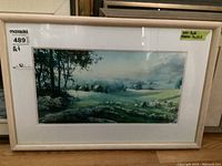 Framed pastoral art print featuring a peaceful countryside scene with sheep and barns, in a white wooden frame with glass, photo taken to show overall condition and framing.