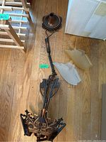 Full view of the disassembled vintage metal hanging light fixture showing metal frame and three amber glass shades on wood floor.
