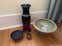 Four signed pottery pieces displayed including a tall vase, large footed bowl, small cup, and shallow bowl