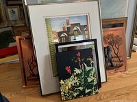 Seven framed prints on the floor including floral prints, the milkmaid reproduction, elephant figures on copper, and winter wagon scene.