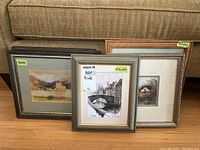 Three framed prints including one with a Brugge canal scene in a decorative frame, one bird nest scene, and another print of a castle landscape, all behind glass.