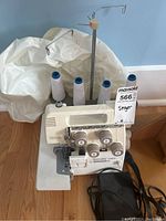 Front view of serger with spool stand, foot pedal and thread cones