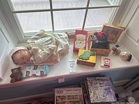 Overview of all items displayed on a window ledge including the doll, sewing machine figurine, boxes, small figurines, puzzle box, and Santa card.