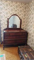 Full dresser showing its three drawers, castor wheels, and attached arched mirror in wooden frame.