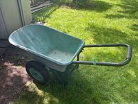 Side view showing the green plastic tub, black metal frame, and handles with grips; located on grass outside.