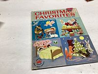 Front cover of the 1951 Christmas Favorites book showing colorful Christmas themed illustrations including Santa, children, animals, and gifts.