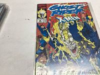 Photo of the front cover of Ghost Rider #26 comic book showing vibrant artwork with Ghost Rider and X-Men characters.