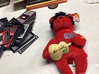 Elvis Presley Ty Beanie Baby plush red bear holding gold guitar with printed autograph.