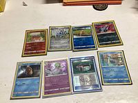 Eight shiny Pokémon cards displayed on a white surface, showing the front faces of the cards. Cards include Gible, Bronzor, Skitty, Crobat, Psyduck, Gardevoir, Unidoll, and Exploud.