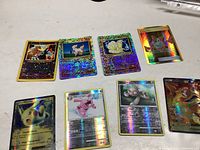 Eight holo Pokémon cards laid out in two rows on white surface