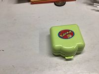 Closed green compact case with Pokémon sticker on top.