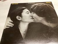 Front cover sleeve shows a black and white close-up photograph of John Lennon and Yoko Ono kissing.