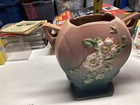 Roseville pottery vase with floral motifs, matte glaze, and dual handles.