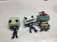 Three loose Funko Pop figures from Nightmare Before Christmas set, featuring two Jack Skellington variants and one blue character with propeller hat, all on white background