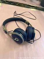 Blue wired Beats headphones shown on flat surface with ear cups and headband visible