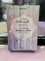 Photo of boxed Merkury Innovations curtain lights showing product packaging and branding.