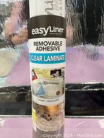 Photo of Easy Liner brand roll packaging showing removable adhesive clear laminate label and sample applications.