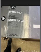 Photo of the HomeTrends floating shelf box showing brand, dimension, weight capacity, and features.