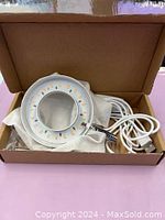 Open box view of circular LED grow light with attached power cord.