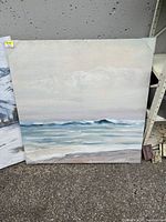 Front view of the large square oil painting showing waves, ocean, sky, and sand with muted colors