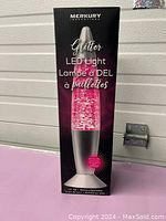 Photo of the Merkury Innovations LED Glitter Light box showing product branding and pink glitter light image.
