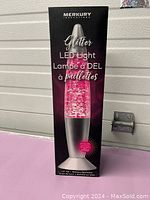 Photo of the boxed Merkury Innovations Glitter LED Light, 14-inch, pink glitter liquid, unopened condition.