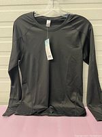 Front view of the black long sleeve shirt with tags showing it is new and size medium.