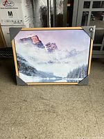 Front view of the new mountain canvas print showing snow-covered peaks and forest with wood frame and corner protectors.