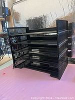 Five black stackable plastic letter trays assembled together showing side ventilation slits.