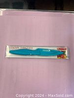 Photo of new Kuhn Rikon paring knife still in original packaging, featuring turquoise handle and matching sheath.