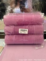Three bundles of pink hair rollers stacked and sealed in plastic packaging.