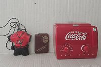 Three vintage novelty radios displayed: Coca-Cola branded radio, Tampa Bay Buccaneers jersey radio, and a brown pawnshop style portable radio. Includes visible dials and wires.