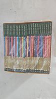Front view showing the spines of 28 books in the Magic Tree House series, all aligned and shrink-wrapped with some plastic peeling.