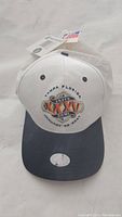 Front view of the white and gray Super Bowl XXXV hat with embroidered logo and attached tags.