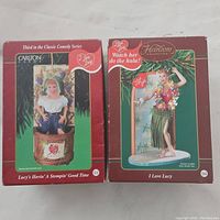 Boxes of two Lucy Carlton Heirloom Collection figurines showing front artwork