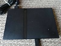 Sony PlayStation 2 console top view showing power cord and slim design.