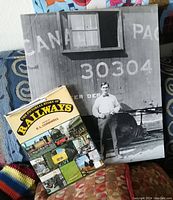 Photo showing the vintage black and white print beside the book on railways, highlighting the conductor and train car details