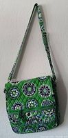 Front view of Vera Bradley cross body bag showing quilted pattern in green with circular floral motifs and adjustable strap.
