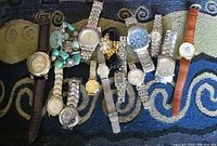Overview photo showing 14 watches of various styles including metal link bands, leather straps, and beaded bracelet style watches.