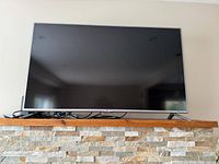 Front view of LG 55-inch flat-screen TV on mantle with cables visible