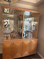 Full view of the Italian-made china cabinet showing wooden paneled lower storage with four doors and upper glass display case with glass shelves and mirrored back.
