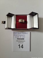 Ring displayed in open presentation box on white background alongside handwritten size and lot number card.